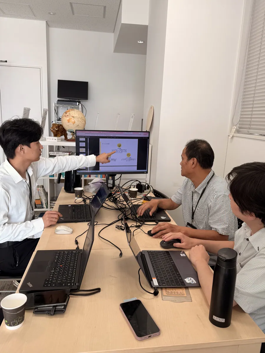 モニターを見ながら意見を交わす社員